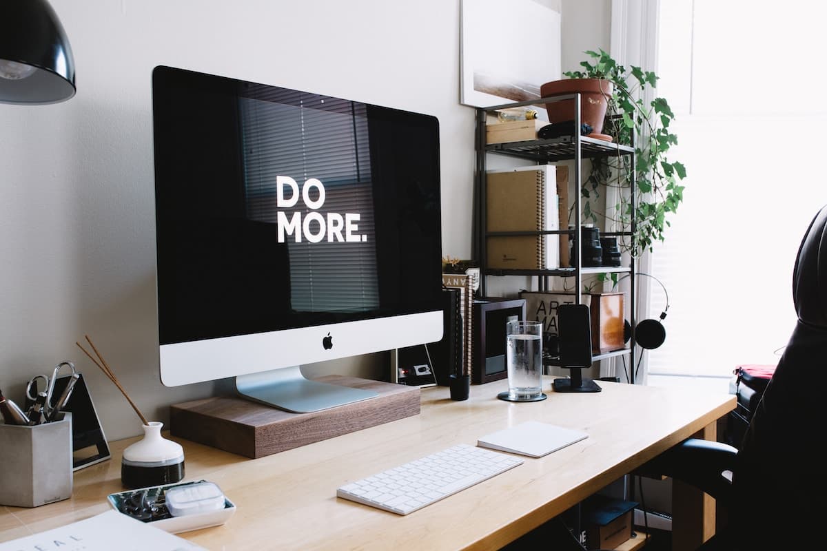 Arbeitstisch mit iMac und dem Schriftzug Do More