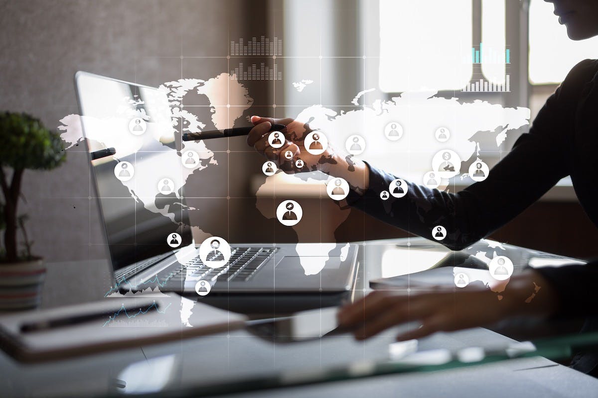 Virtuelle Weltkarte ist über ein Büro gelegt mit einer Person und einem Laptot